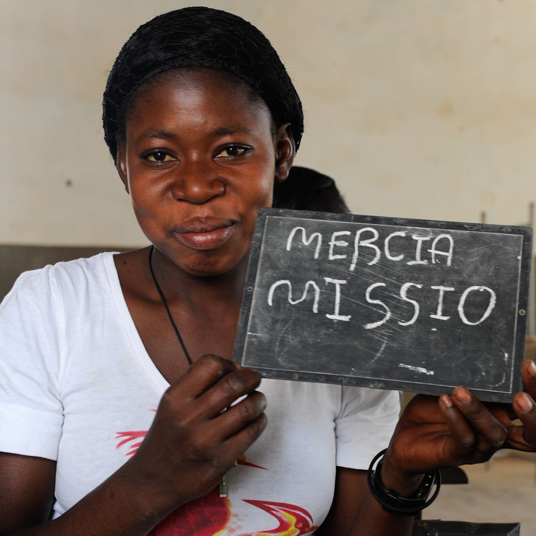Eine Frau aus Burkina Faso hält eine Tafel mit der Aufschrit Merci à missio hoch. Foto: Joerg Boethling