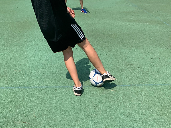 Beine eines Jungen in Sportkleidung, der gerade im Ballbesitz ist.
