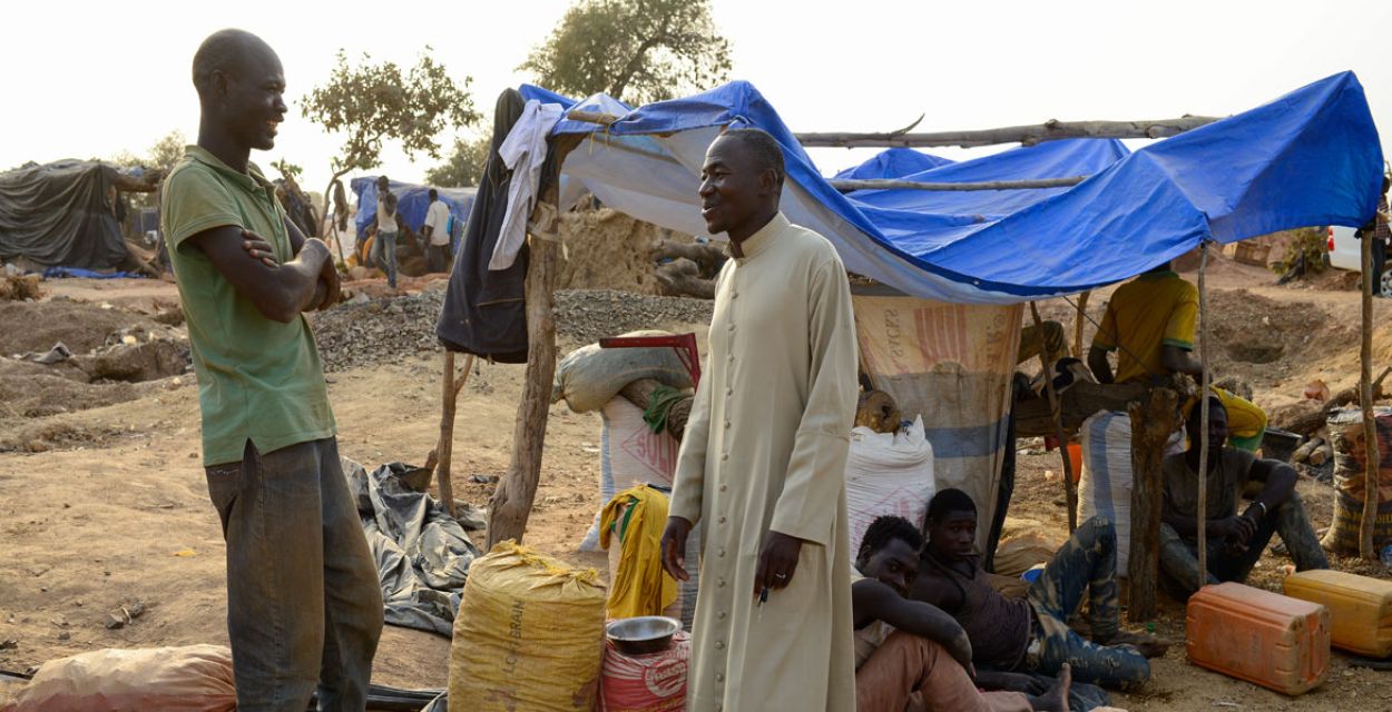 Ein Priester und ein weiterer Mann aus einem afrikanischen Land stehen vor einem provisorischen Zelt.