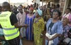 Flüchtlinge in Kampala hören aufmerksam einem Mitarbeiter des Jesuiten Flüchtlingsdienstes Uganda zu. In der ersten Reihe stehen drei ältere Frauen in afrikanischen Gewändern.